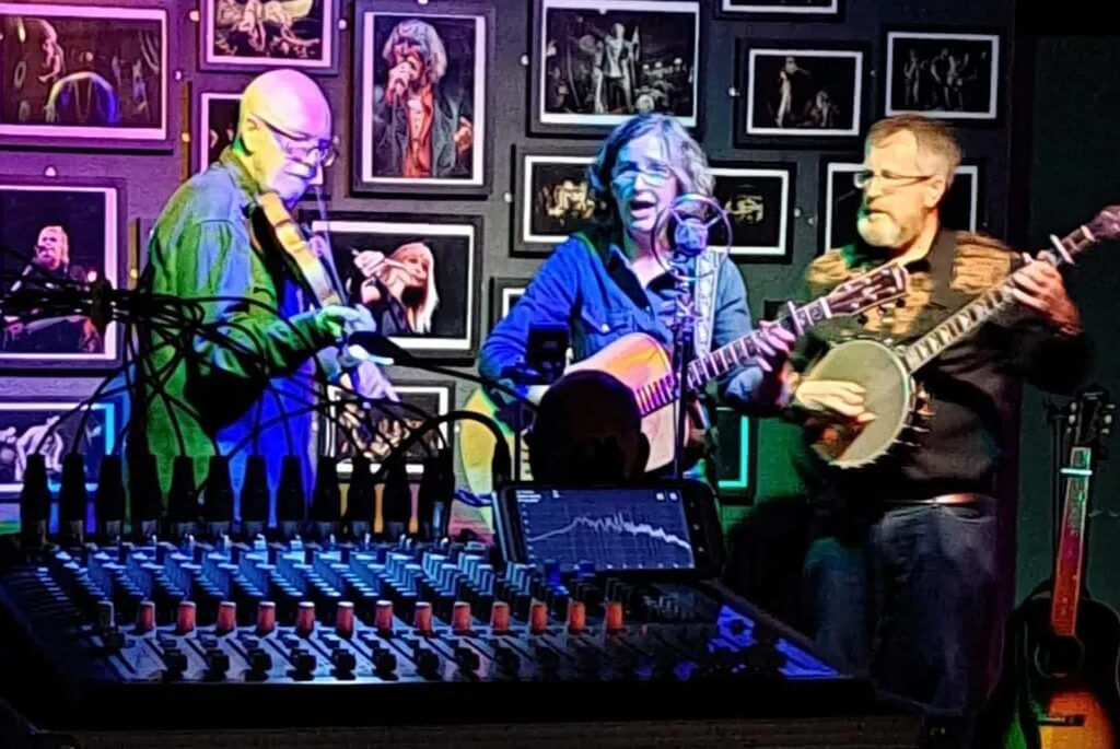 Three musicians playing fiddle, guitar and banjo