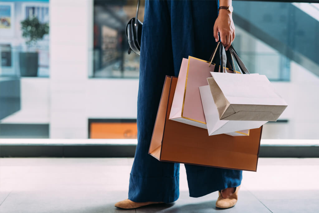 Cropped, waist-down shot of woman holding multiple shopping bags