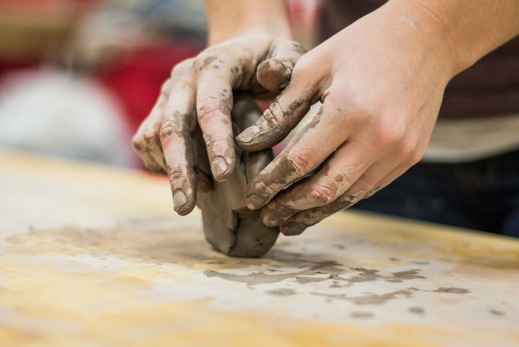 Hands shaping a ball of clay
