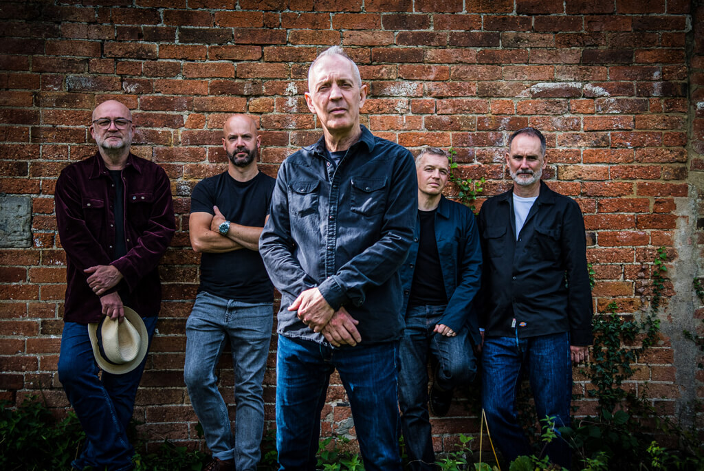 Raindogs band promo pic - five men in front of a brick wall