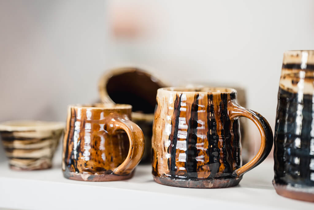 Group of Pottery mugs on a shelf, brown and yellow glaze