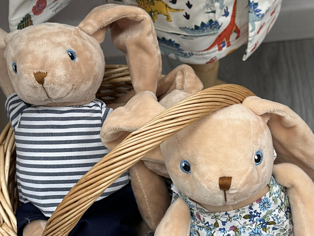 Two fawn coloured cuddly rabbit toys in a basket