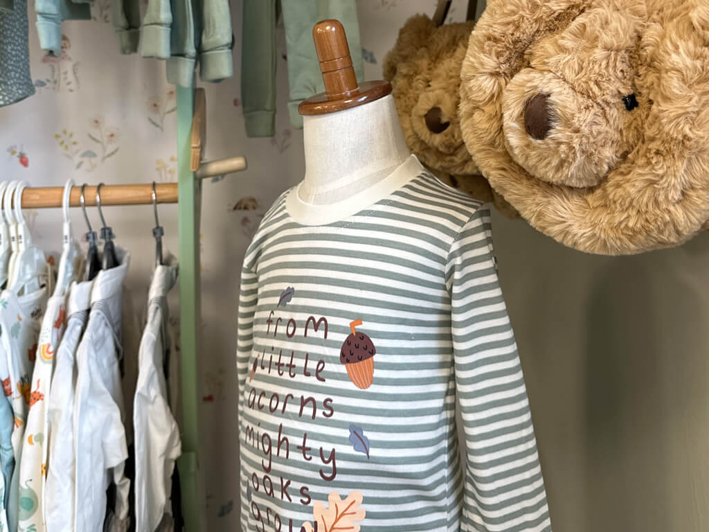 Young children's clothes on hangers in a shop. Teddy bear bags also