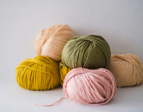 Collections of balls of various coloured yarns - pale pink, greens and creams