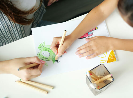 Two children drawing together, only arms and artwork can be seen