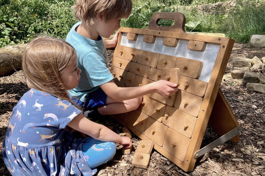 Young boy and his sister solving a wooden puzzle outdoors